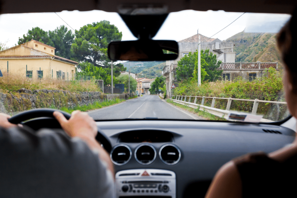 View from inside a car driving down a rural road in the UK, showcasing narrow lanes and countryside scenery.